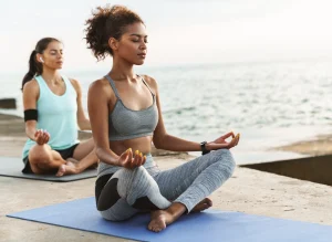 Image of two women meditating while practicing holistic fitness