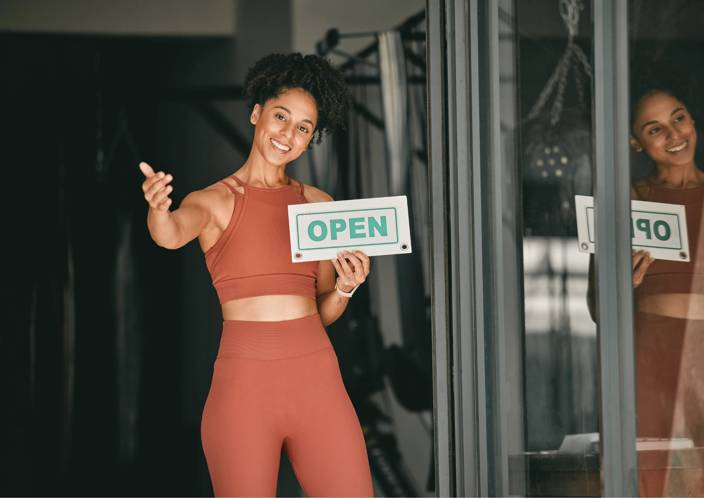 Image of a woman opening a gym and welcoming people in