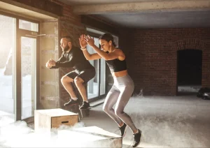 Image of a man and woman doing box jumps in a circuit training class