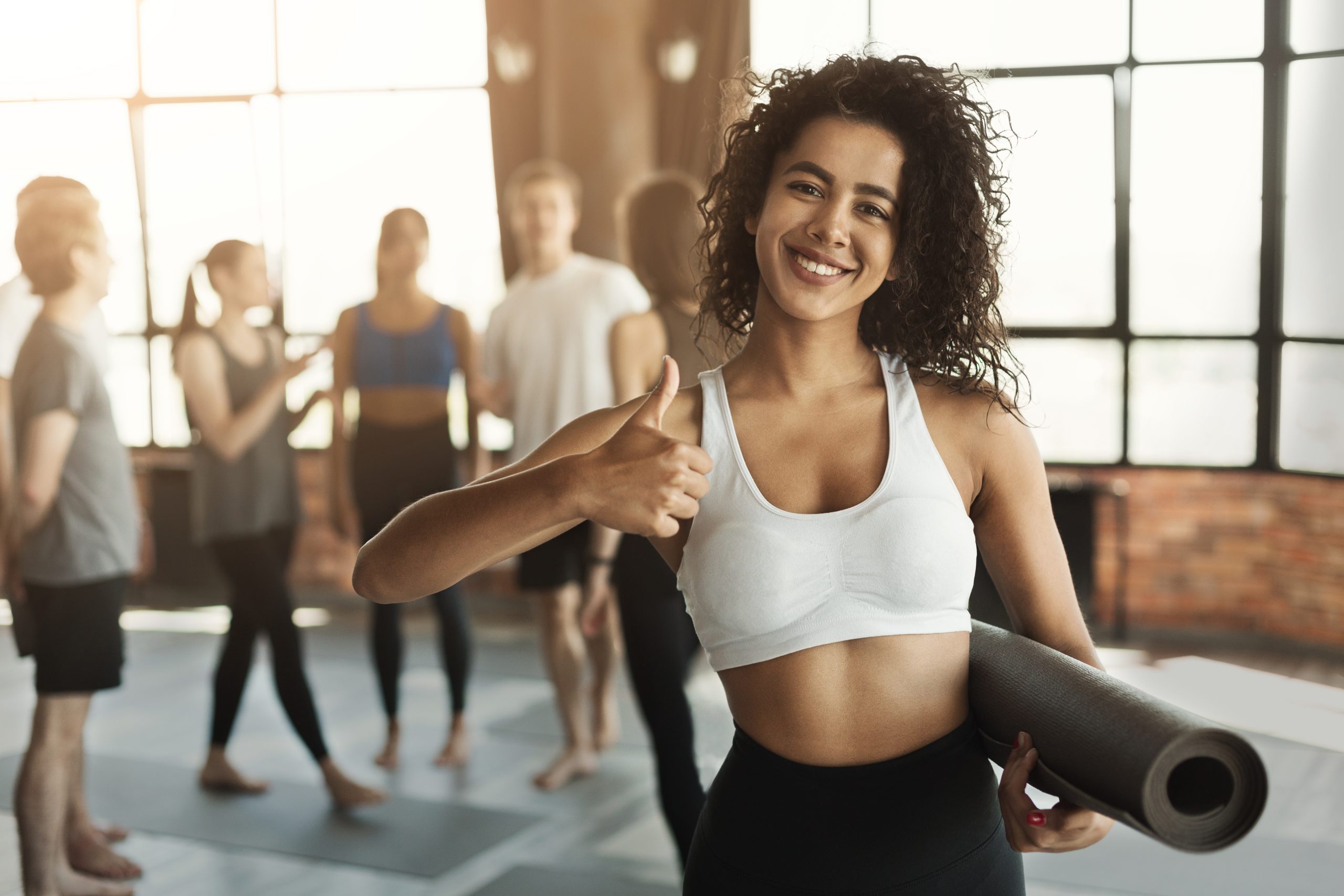 Image of woman ready for her pilates workout with mat and thumbs up