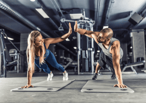 Image of a man and woman high-fiving while working out at the gym