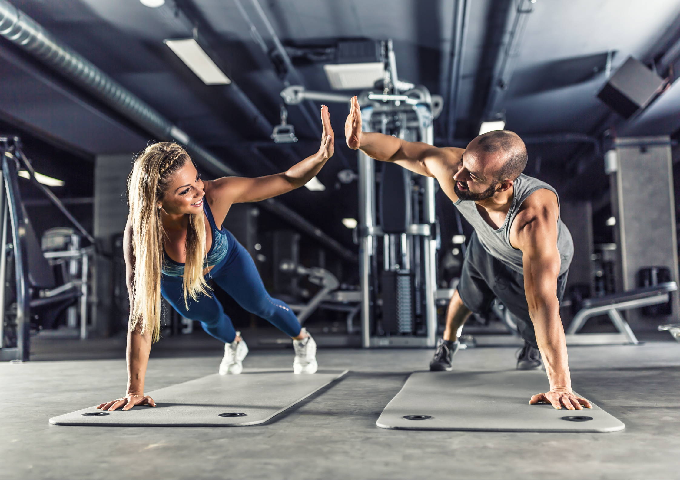 Image of a man and woman high-fiving while working out at the gym