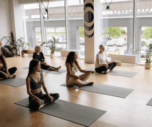 Image of members sitting on yoga mats in a yoga studio class