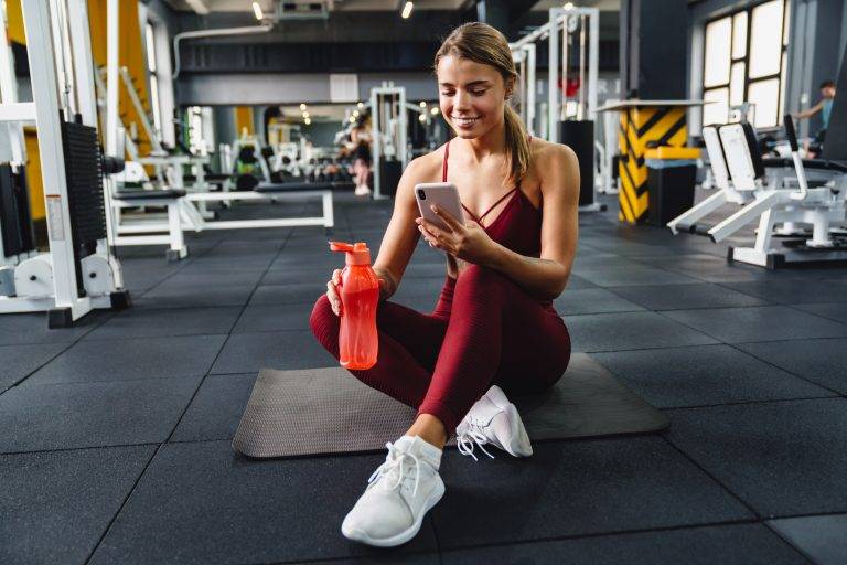 Image of a woman using a gym mobile app while working out