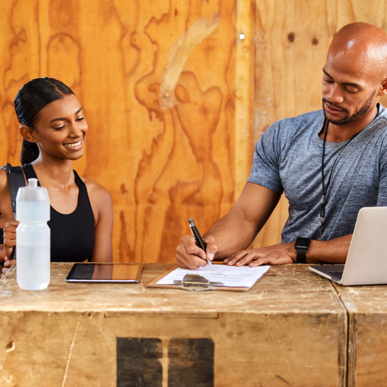 Image of a trainer sign in member taking attendance using gym attendance tracking software